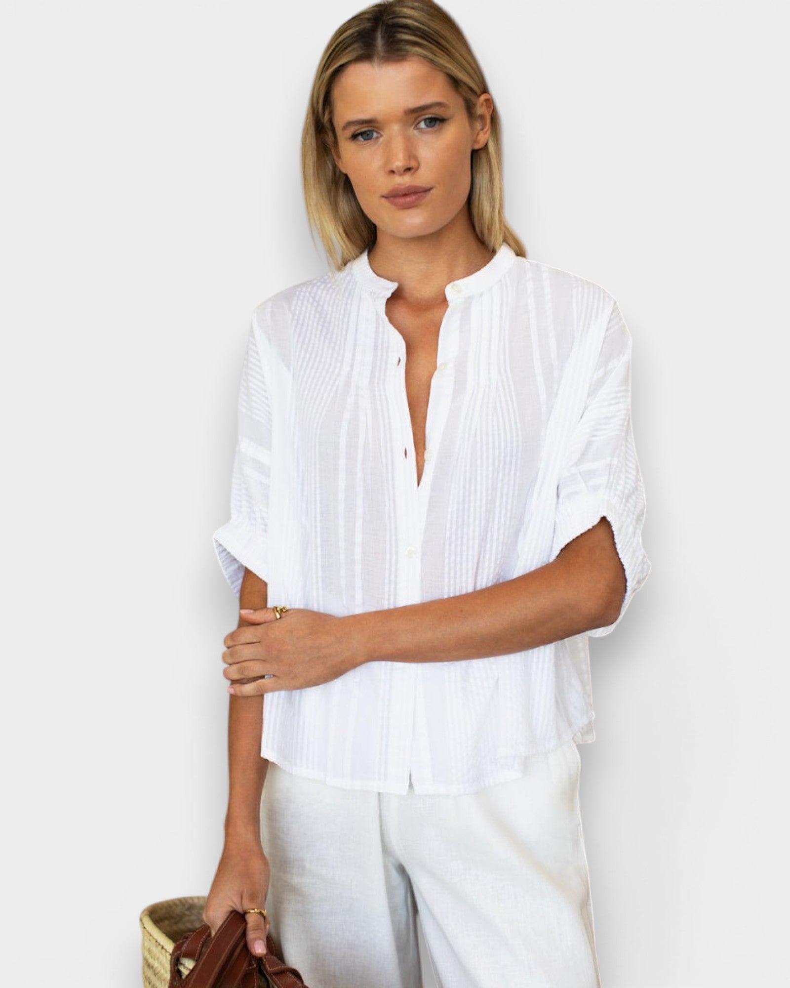Model wearing a white JONES + CO organic cotton seersucker top with a mandarin collar and dolman half sleeves.