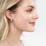 JONES + CO 14K gold chunky square tube hoop earrings worn by a blonde woman.