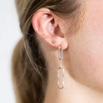 JONES + CO 14K gold paper clip dangle earrings featuring a small sparkling diamond on a woman's ear