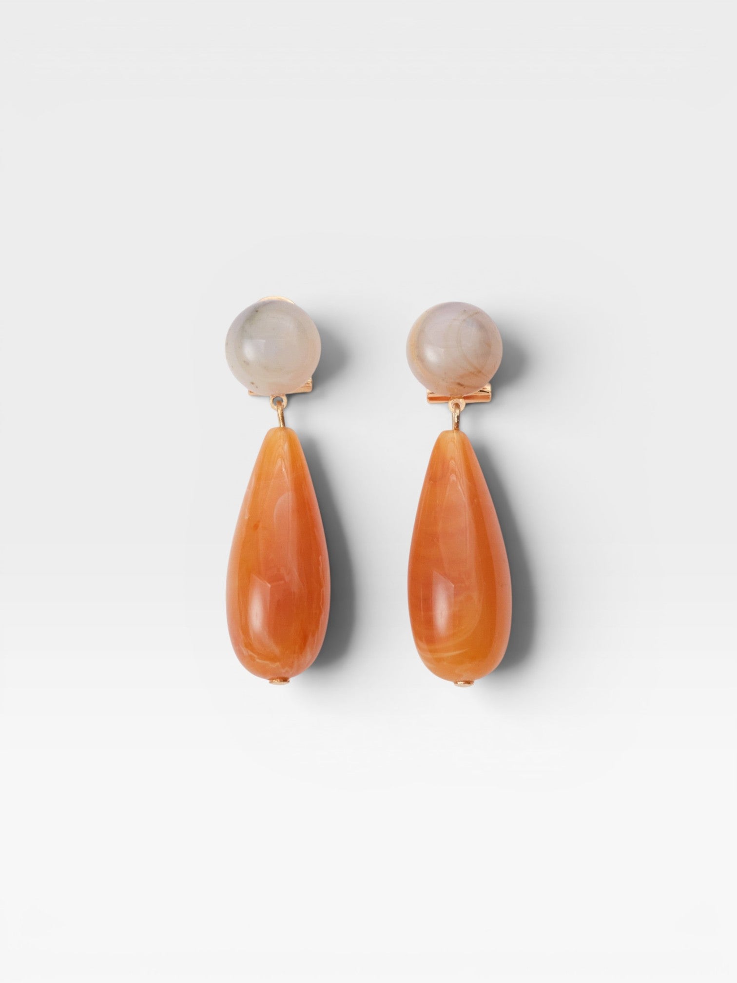 JONES + CO Pamploma earrings with cream spherical studs and orange tear-shaped acrylic drops.