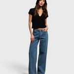 Model wearing JONES + CO Alanis V-neck cropped black recycled cotton tee with wide-leg blue jeans