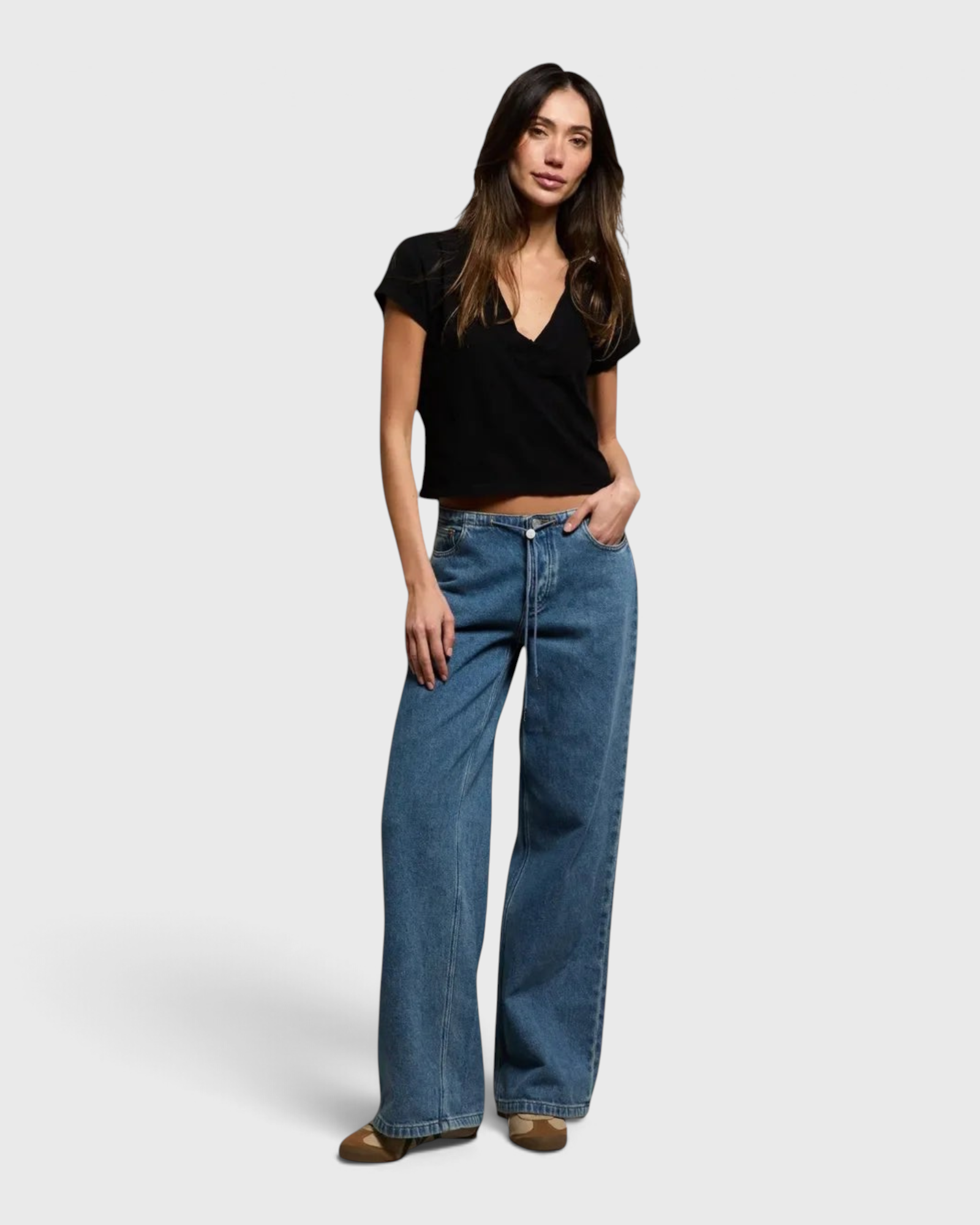 Model wearing JONES + CO Alanis V-neck cropped black recycled cotton tee with wide-leg blue jeans