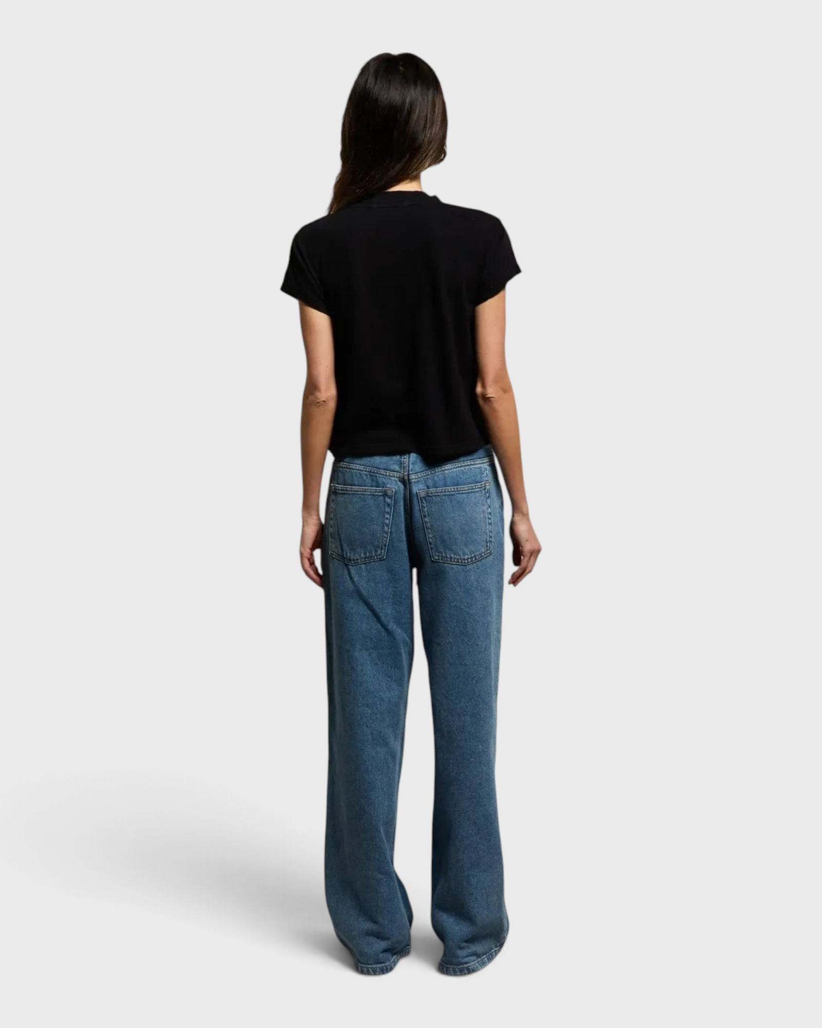 JONES + CO Alanis V Neck tee in true black recycled cotton, shown from the back with blue denim jeans.