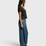 JONES + CO Alanis V-neck tee in vintage black recycled cotton, worn by a model in profile with wide-leg blue jeans.