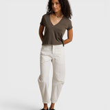 Model wearing a JONES + CO dark olive recycled cotton Alanis V-neck tee with a relaxed cropped fit and white trousers.