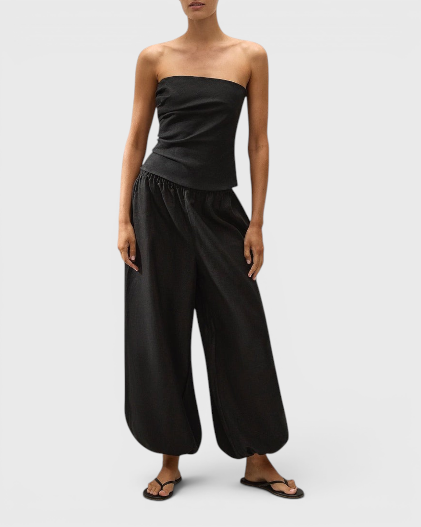 JONES + CO black strapless linen Alzira top with asymmetric front pleats and back tie detail on a model