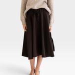 JONES + CO Angie skirt in chocolate brown with drawstring waist, side pockets, and slits, worn with a knit sweater.