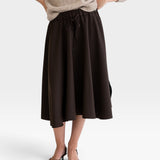 JONES + CO Angie skirt in chocolate brown with drawstring waist, side pockets, and slits, worn with a knit sweater.