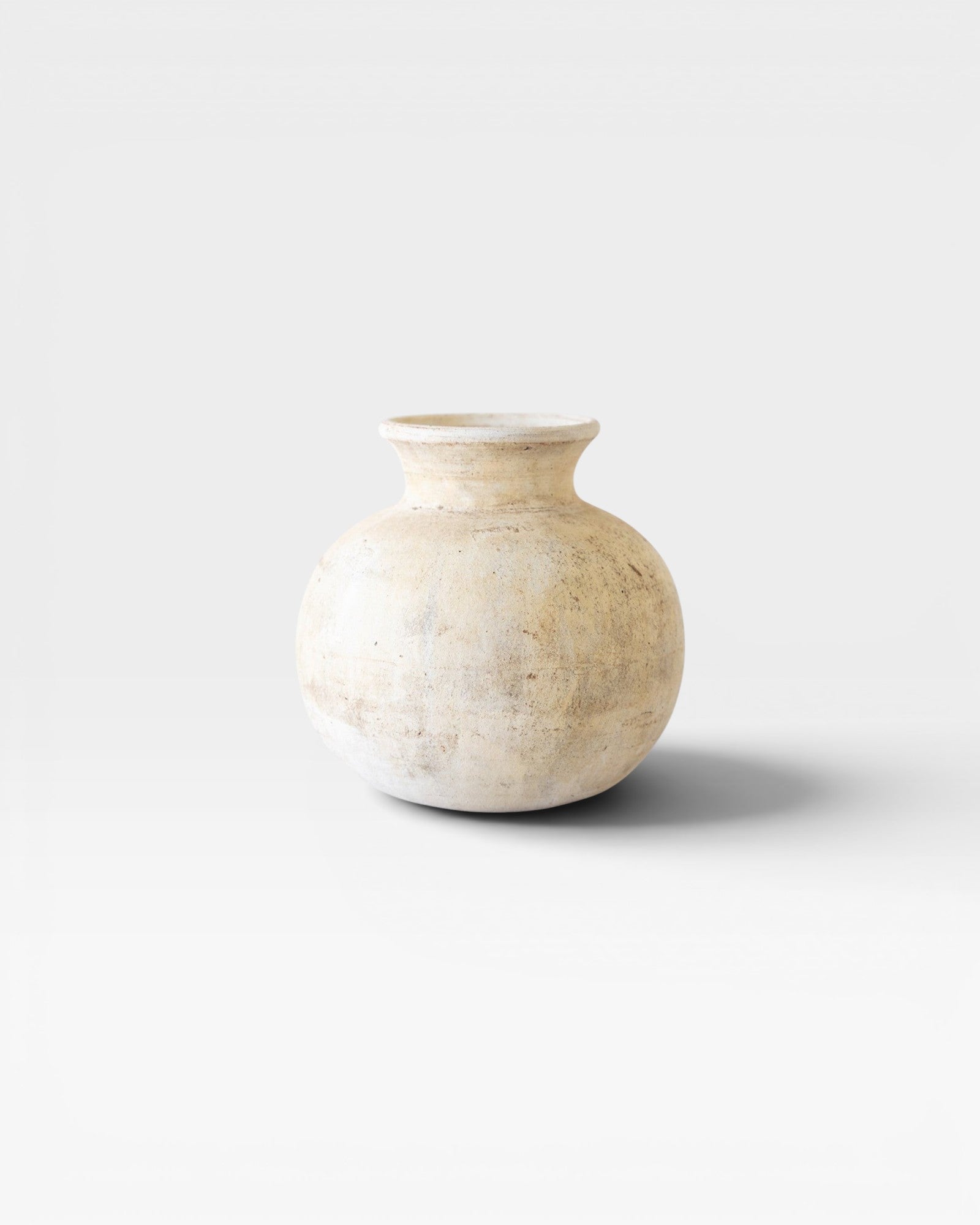 JONES + CO antique clay water pot with a rounded silhouette and weathered patina, neutral beige color.