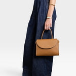 JONES + CO Archive 1978 Linea top handle bag in gianduia brown pebbled leather with flap closure and cotton canvas lining.