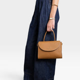 JONES + CO Archive 1978 Linea top handle bag in gianduia brown pebbled leather with flap closure and cotton canvas lining.