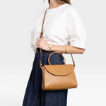 JONES + CO Archive 1978 Linea top handle bag in gianduia brown vegetable-tanned leather with rounded flap and adjustable strap.