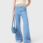 JONES + CO Aria flared jeans in light blue stretch denim with patch pockets and high waist worn with a matching bag.