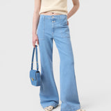 JONES + CO Aria flared jeans in light blue stretch denim with patch pockets and high waist worn with a matching bag.