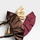 JONES + CO Babette Bag in chocolate, gold, and burgundy satin with ruched detailing. Fits essentials for a night out.