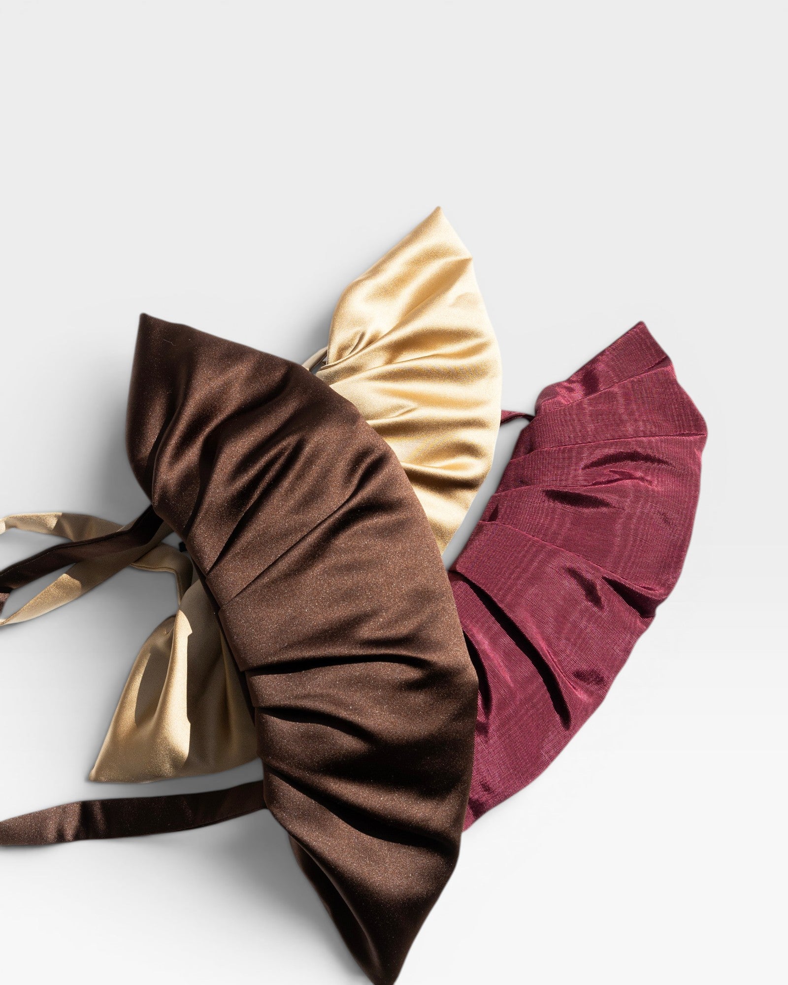 JONES + CO Babette Bag in chocolate, gold, and burgundy satin with ruched detailing. Fits essentials for a night out.