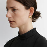JONES + CO Baby Keel Hoop earrings in gold. Mini hollow oblong hoops with hinged fastening.