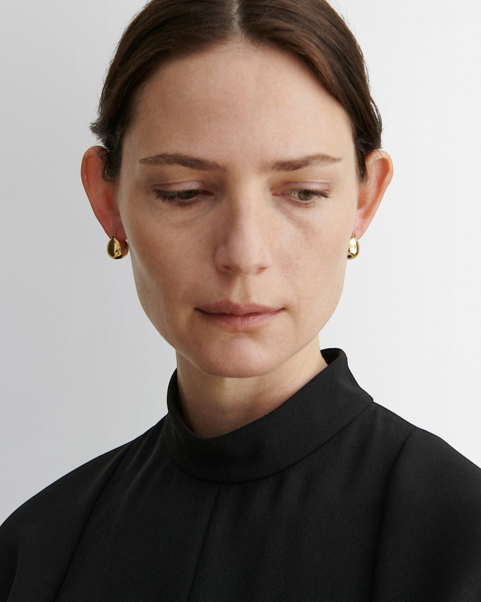 JONES + CO Baby Keel Hoop gold hollow oblong hoop earrings with hinged fastening.