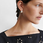 JONES + CO Baby Keel Hoop mini hollow oblong silver hoop earrings with hinged fastening.