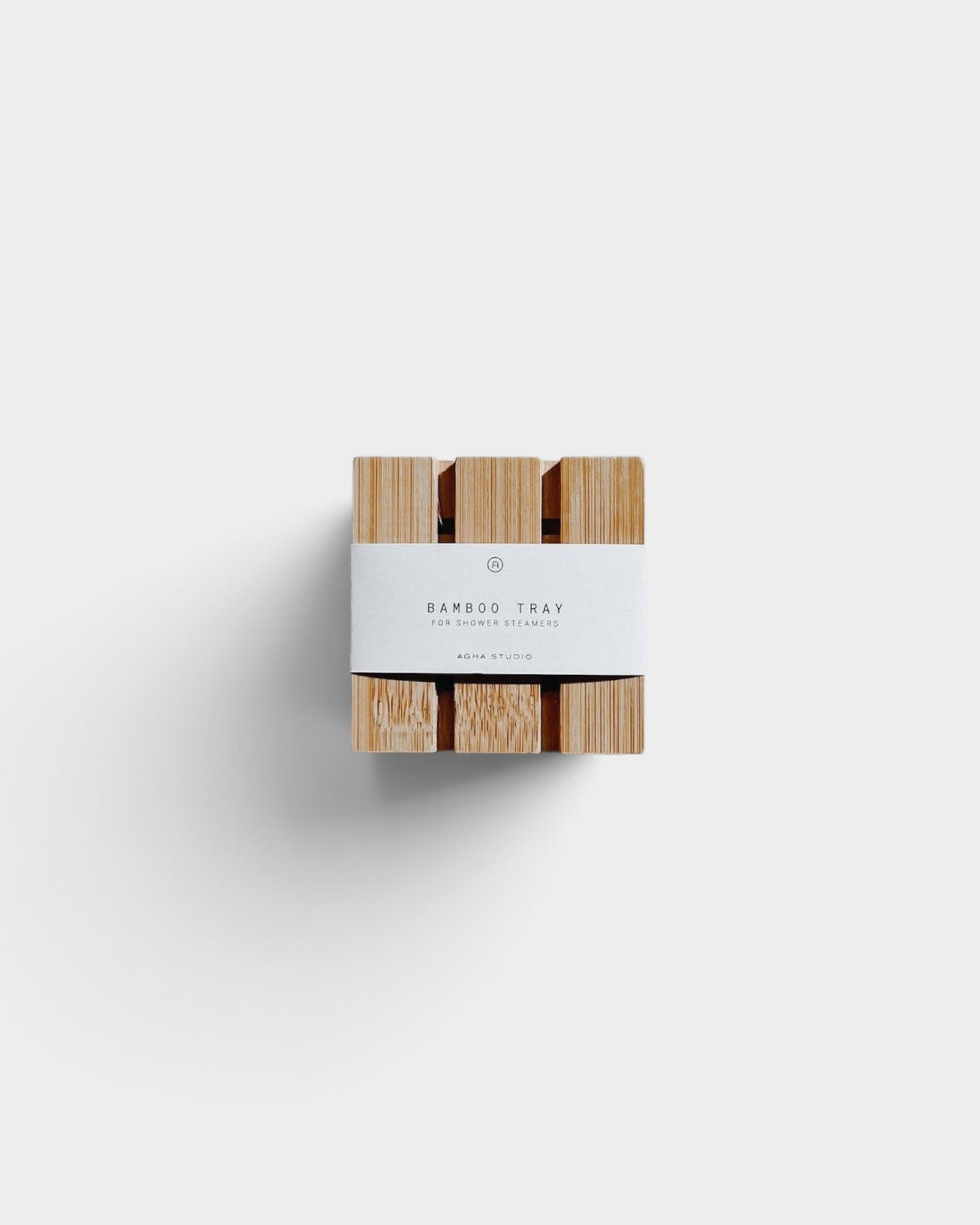 JONES + CO bamboo shower steamer tray with a white paper band, top-down view on a neutral background.