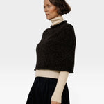 JONES + CO seamless basalt alpaca-blend poncho worn over a cream turtleneck sweater by a woman in profile view
