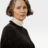 JONES + CO seamless basalt alpaca-blend poncho worn over a cream turtleneck by a woman with short grey hair