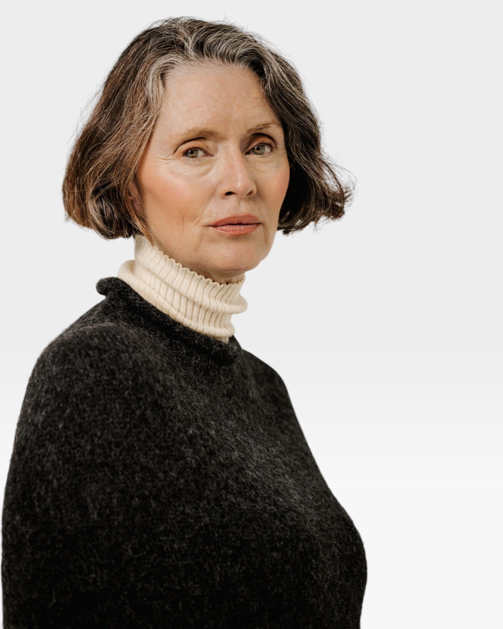 JONES + CO seamless basalt alpaca-blend poncho worn over a cream turtleneck by a woman with short grey hair