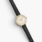 JONES + CO Beverly watch featuring a minimalist gold case, cream dial with index markers, and a black leather strap.