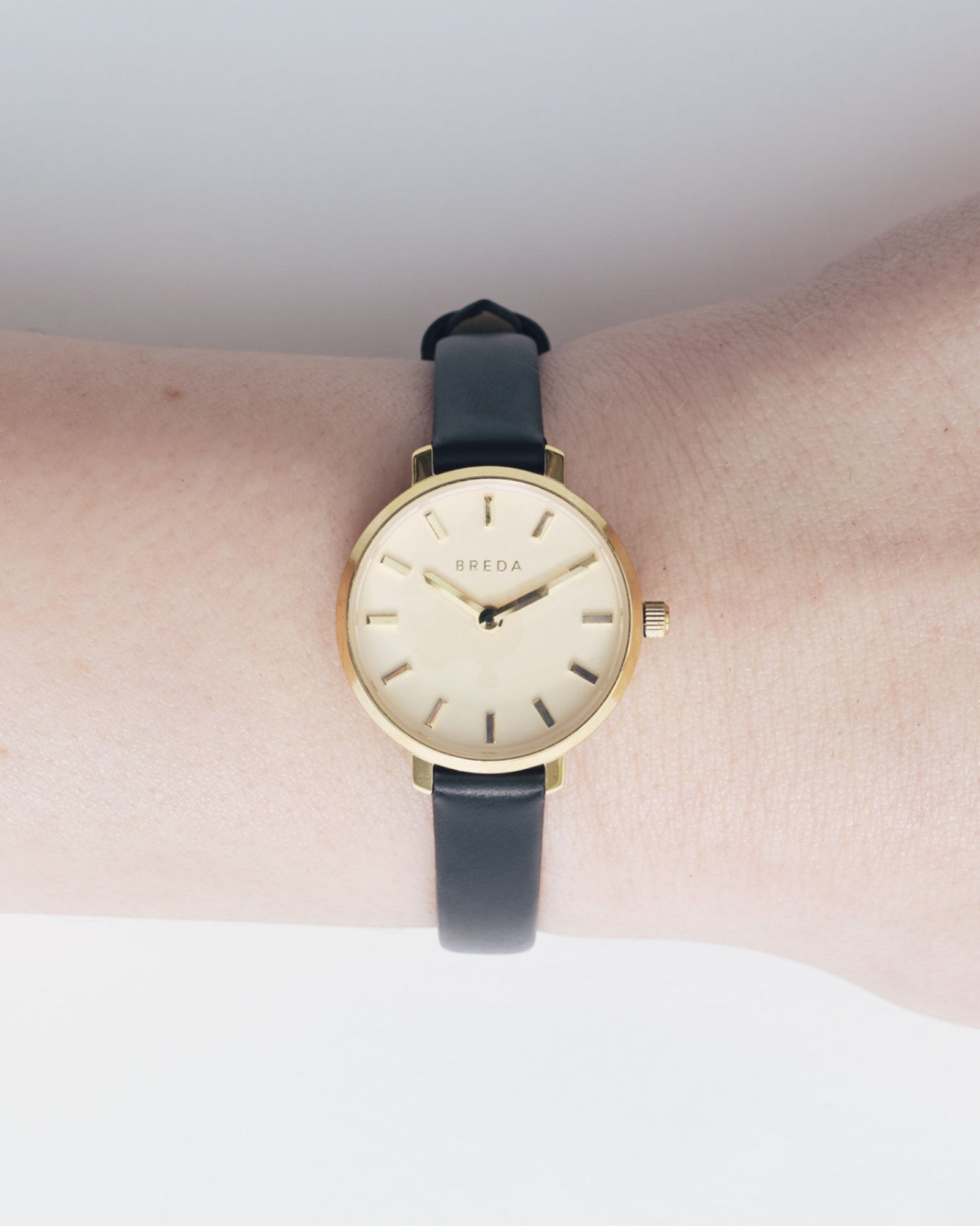 JONES + CO Beverly watch featuring a minimalist gold case and black leather strap worn on a wrist.