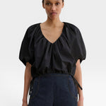 JONES + CO black organic cotton poplin cropped V-neck top with voluminous balloon sleeves and adjustable waist ties.