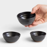 JONES + CO handcrafted black ceramic little bowls held in a hand, perfect for snacks or home decor.