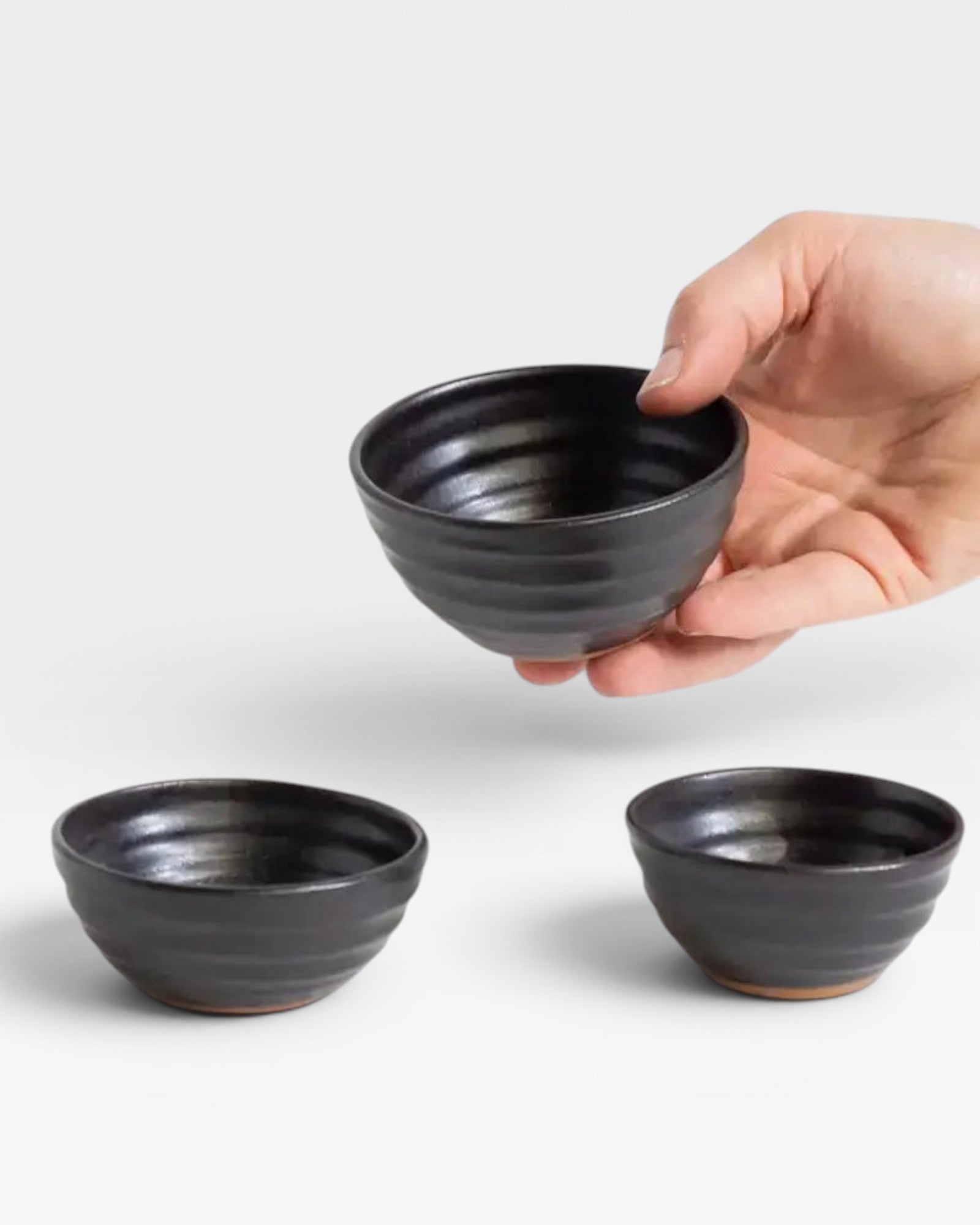 JONES + CO handcrafted black ceramic little bowls held in a hand, perfect for snacks or home decor.