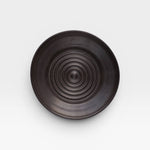JONES + CO black ceramic garlic grater plate with a circular ridged center for grating garlic and herbs.