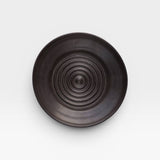 JONES + CO black ceramic garlic grater plate with a circular ridged center for grating garlic and herbs.