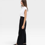 JONES + CO black high-waisted wide-leg cotton trousers with pleats, worn by a model.