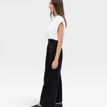 JONES + CO black high-waisted wide-leg cotton trousers with pleats, worn by a model.