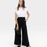 JONES + CO black high-waisted wide-leg cotton trousers with pleats, paired with a white top.
