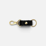 JONES + CO black cowhide keychain with gold-tone metal clasp and ring hardware on a white background.