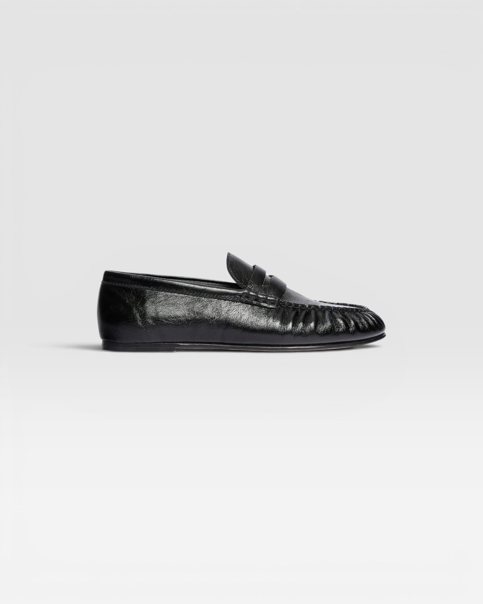 JONES + CO Sydney black crinkle patent leather penny loafer with ruched detailing on a side profile view.