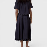 JONES + CO black cotton poplin short sleeve shirt with embroidered cut-out hem, worn with matching midi skirt.