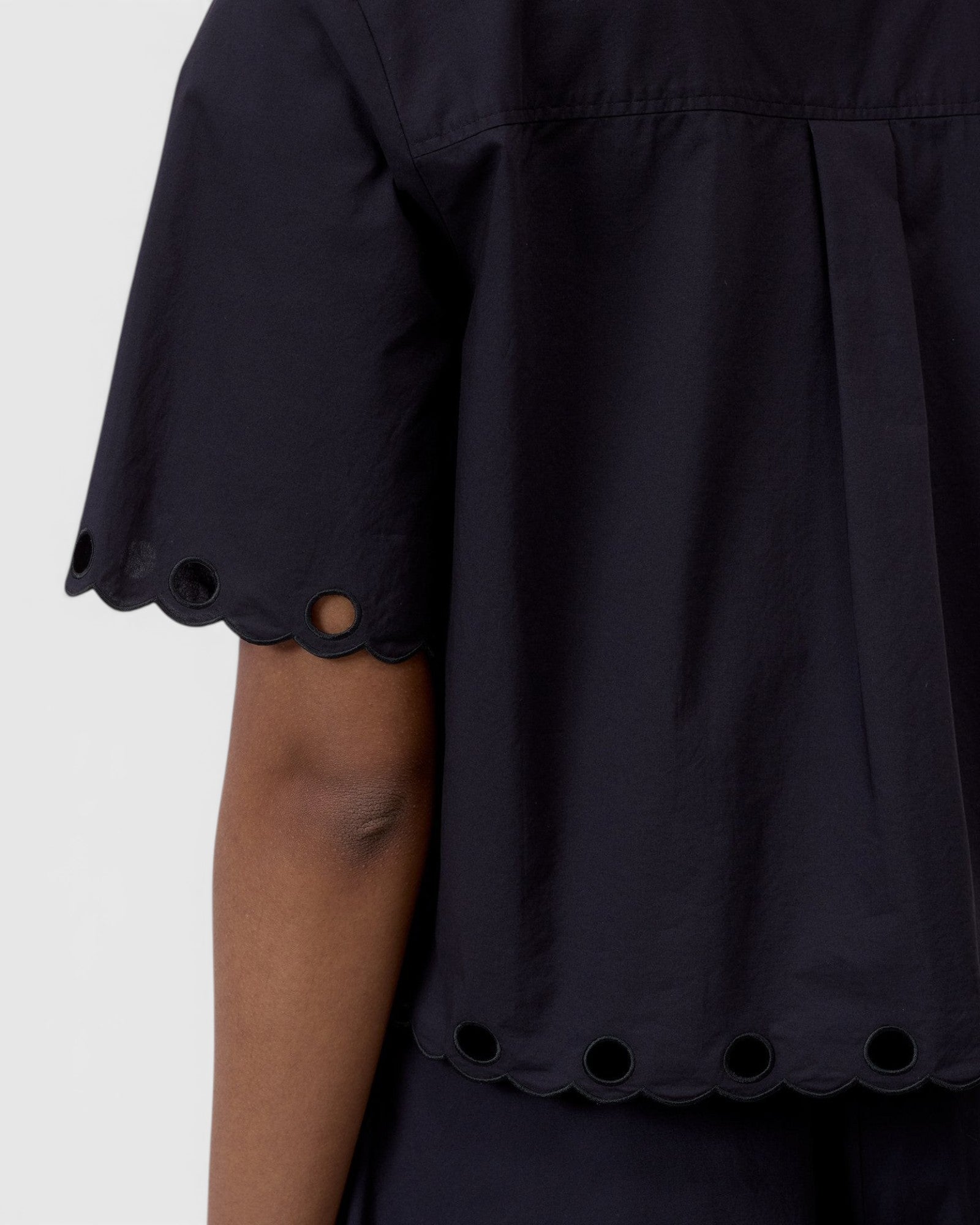 JONES + CO black cotton poplin short sleeve shirt with scalloped hem and eyelet embroidery detail