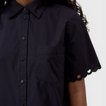JONES + CO black cotton poplin short sleeve shirt with a pointed collar, button placket, and scalloped sleeve detail.