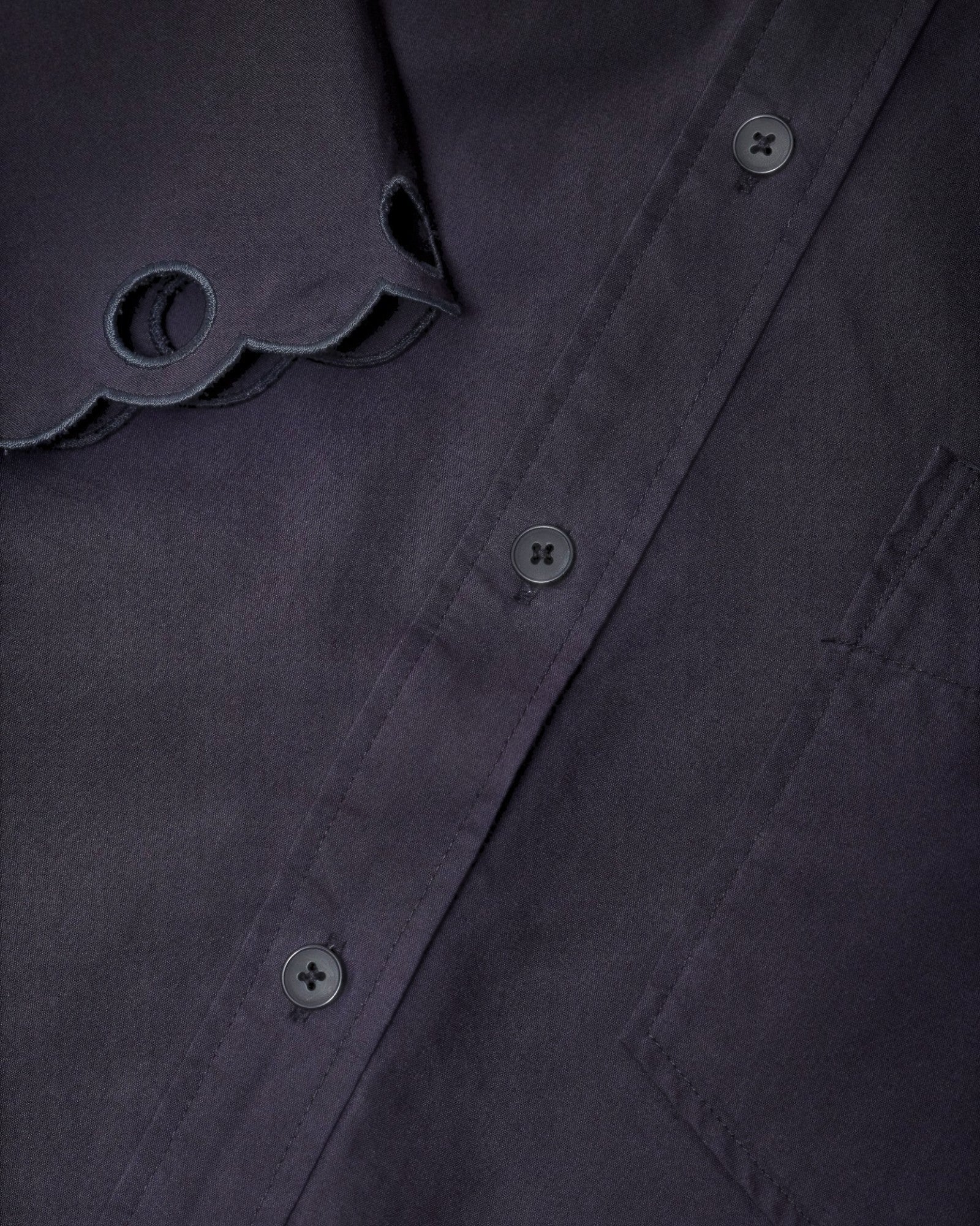 JONES + CO black cotton poplin short sleeve shirt featuring a pointed collar and intricate embroidered scalloped edge.