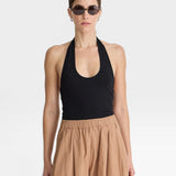 JONES + CO black halter neck bodysuit with a scoop neckline, paired with tan wide-leg pants.