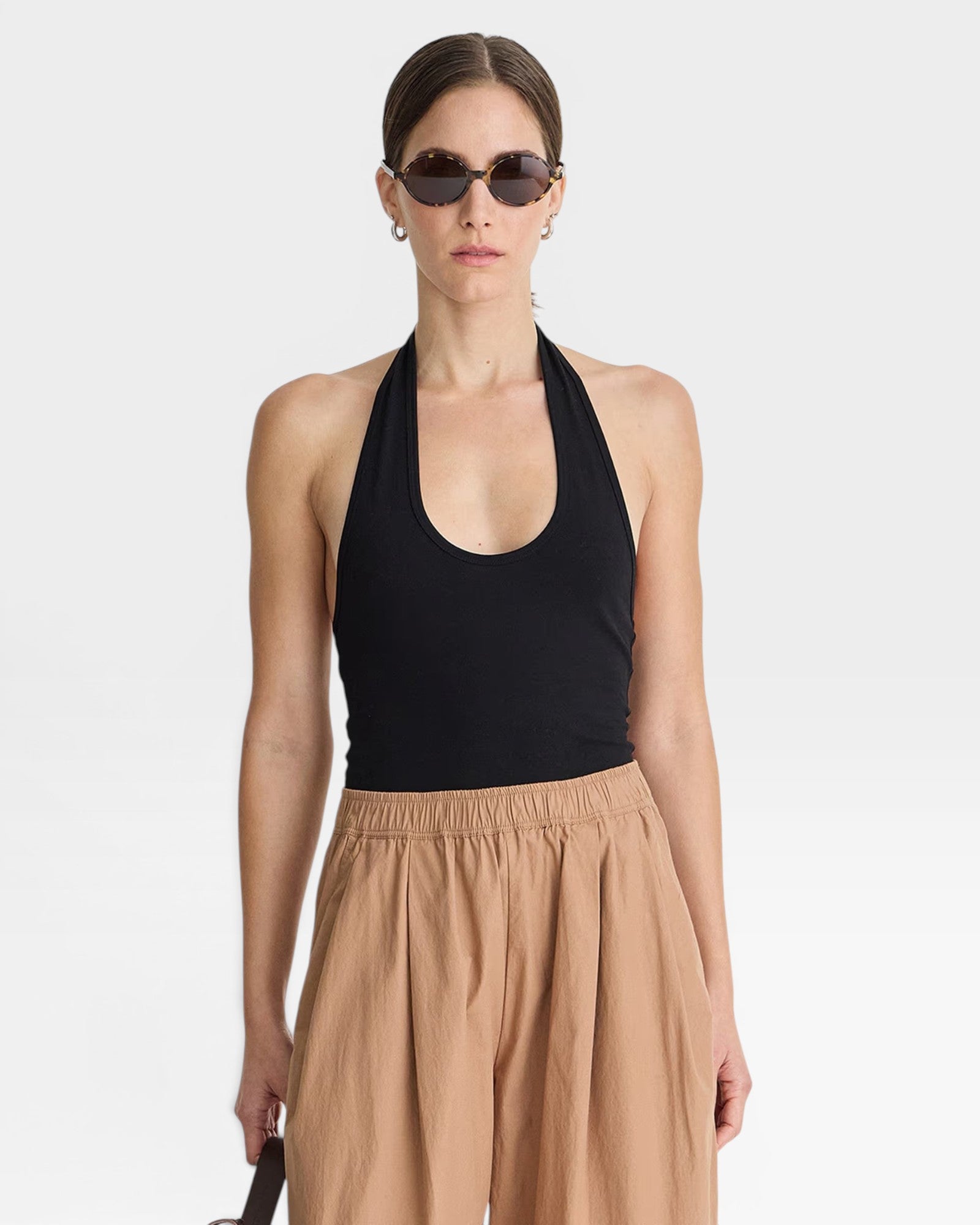 JONES + CO black halter neck bodysuit with a scoop neckline, paired with tan wide-leg pants.