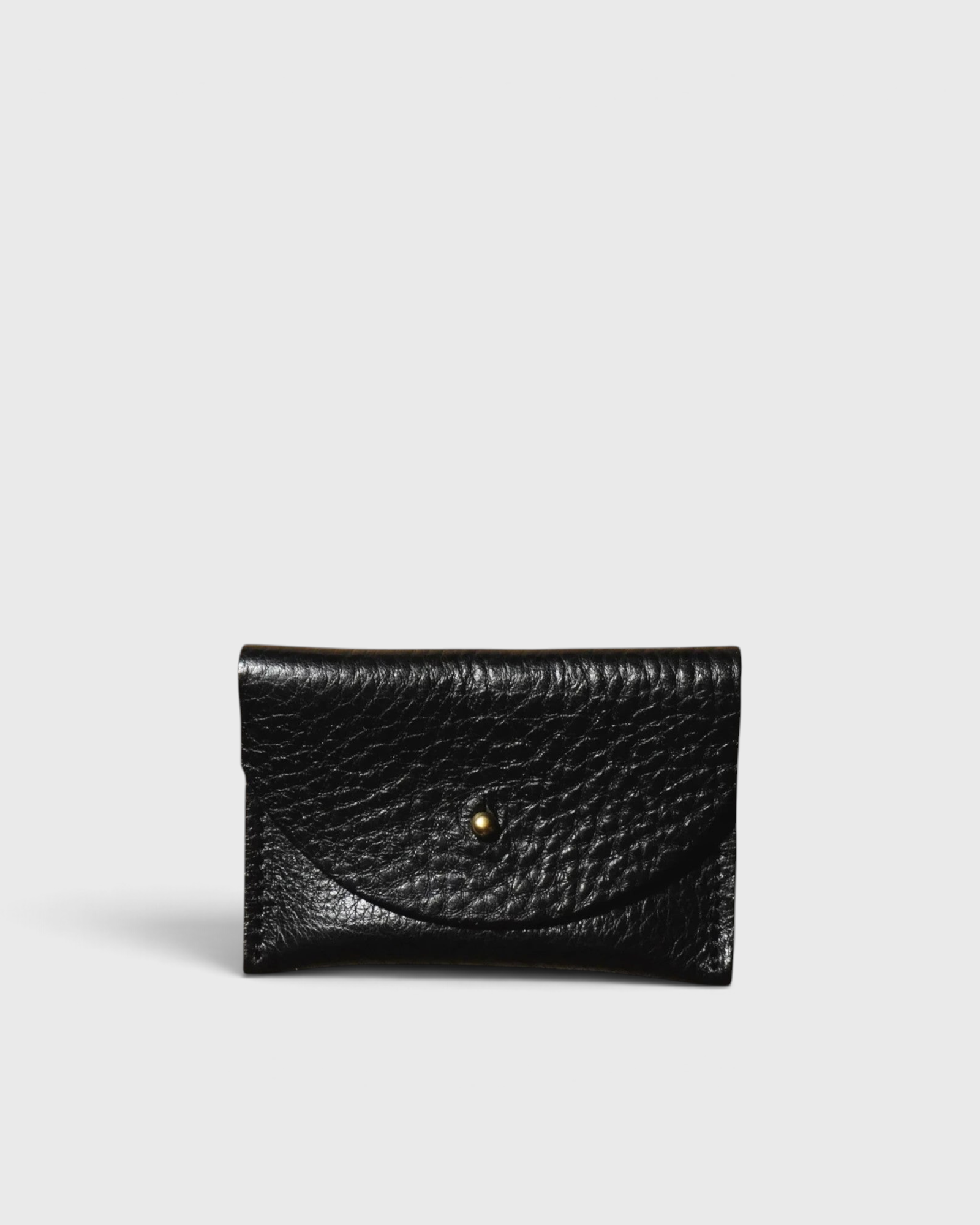 JONES + CO black pebbled leather cardholder with a minimalist envelope flap and gold stud closure.