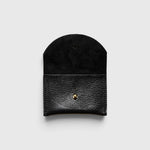 JONES + CO black leather cardholder with a rounded flap and gold snap button closure on a light grey background.