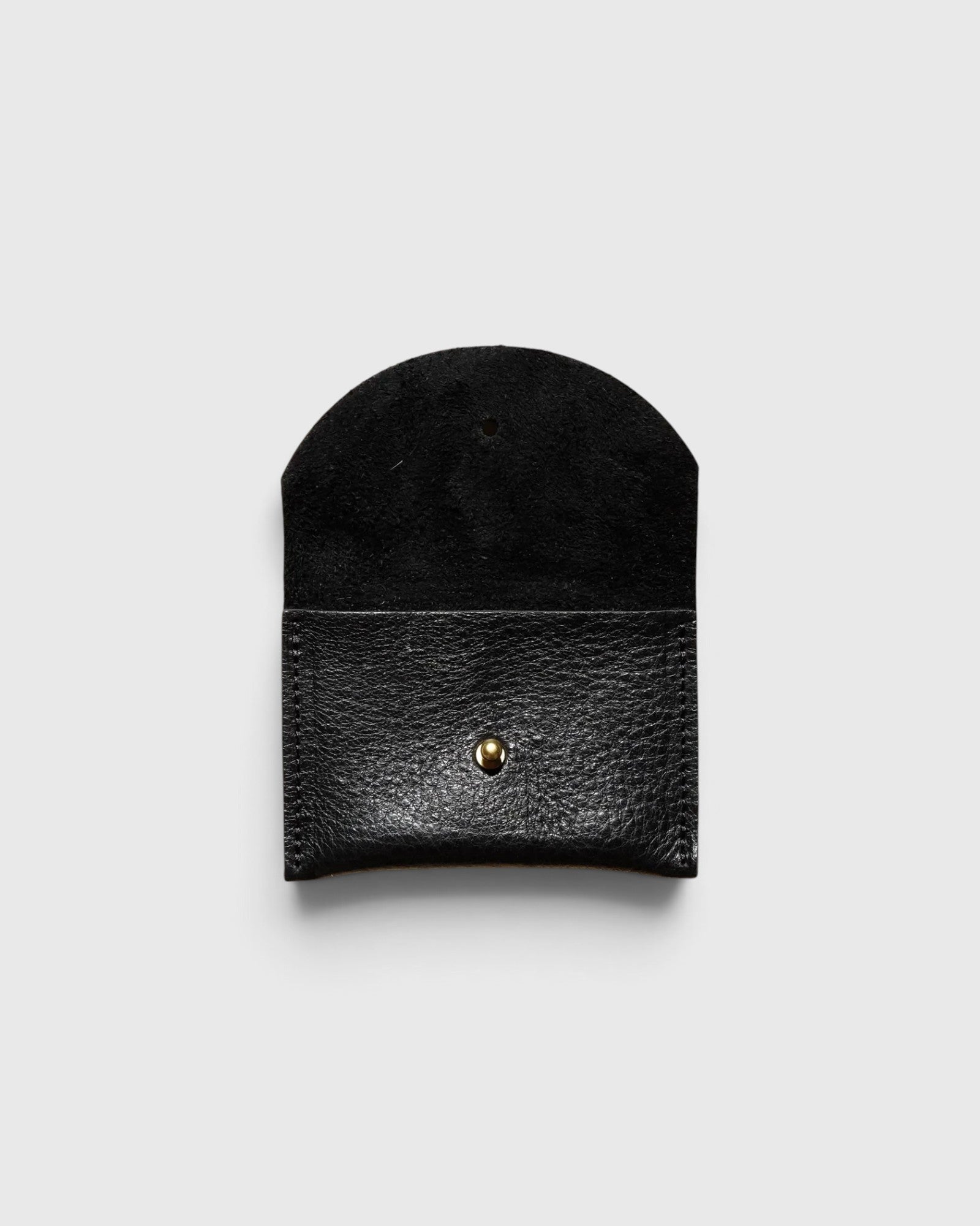 JONES + CO black leather cardholder with a rounded flap and gold snap button closure on a light grey background.