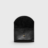 JONES + CO black leather cardholder with a rounded flap and gold snap button closure on a light grey background.