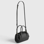 JONES + CO Oyster mini duffle bag in black pebble leather with gold hardware, top handles, and crossbody strap.